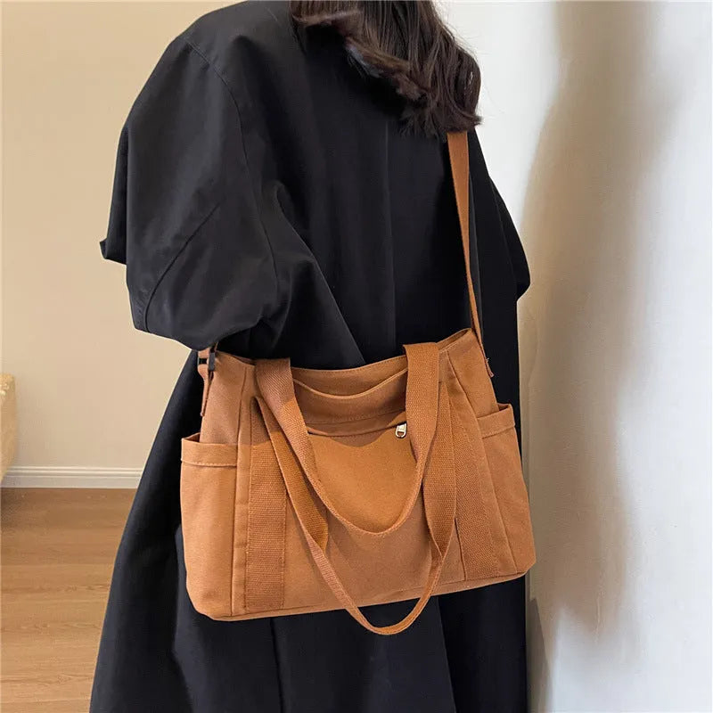 Large black polyester canvas shoulder tote bag showing outer sandwich pocket.