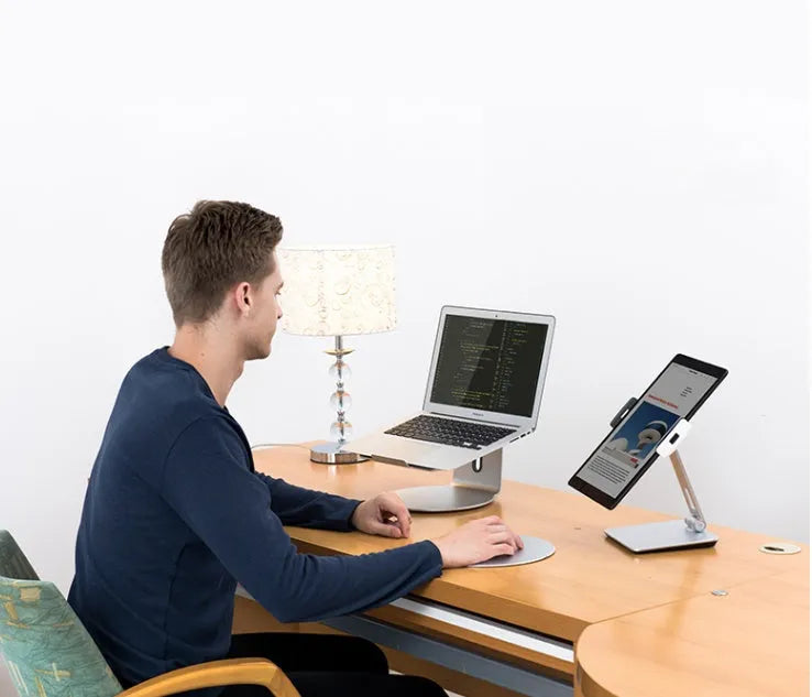Silver foldable aluminium stand holding a tablet at an angle on a desk