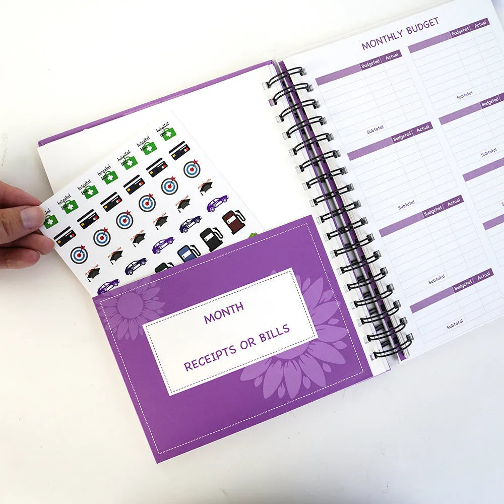 Purple coil-bound financial planning notebook with budget stickers and paper clips