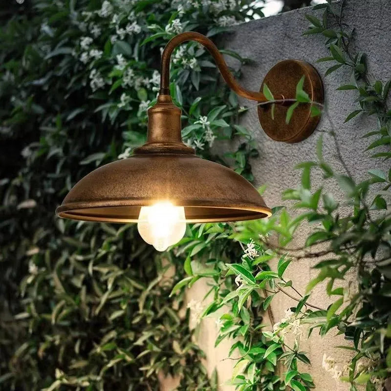Retro style metal wall lamp in copper finish mounted on a stone wall.
