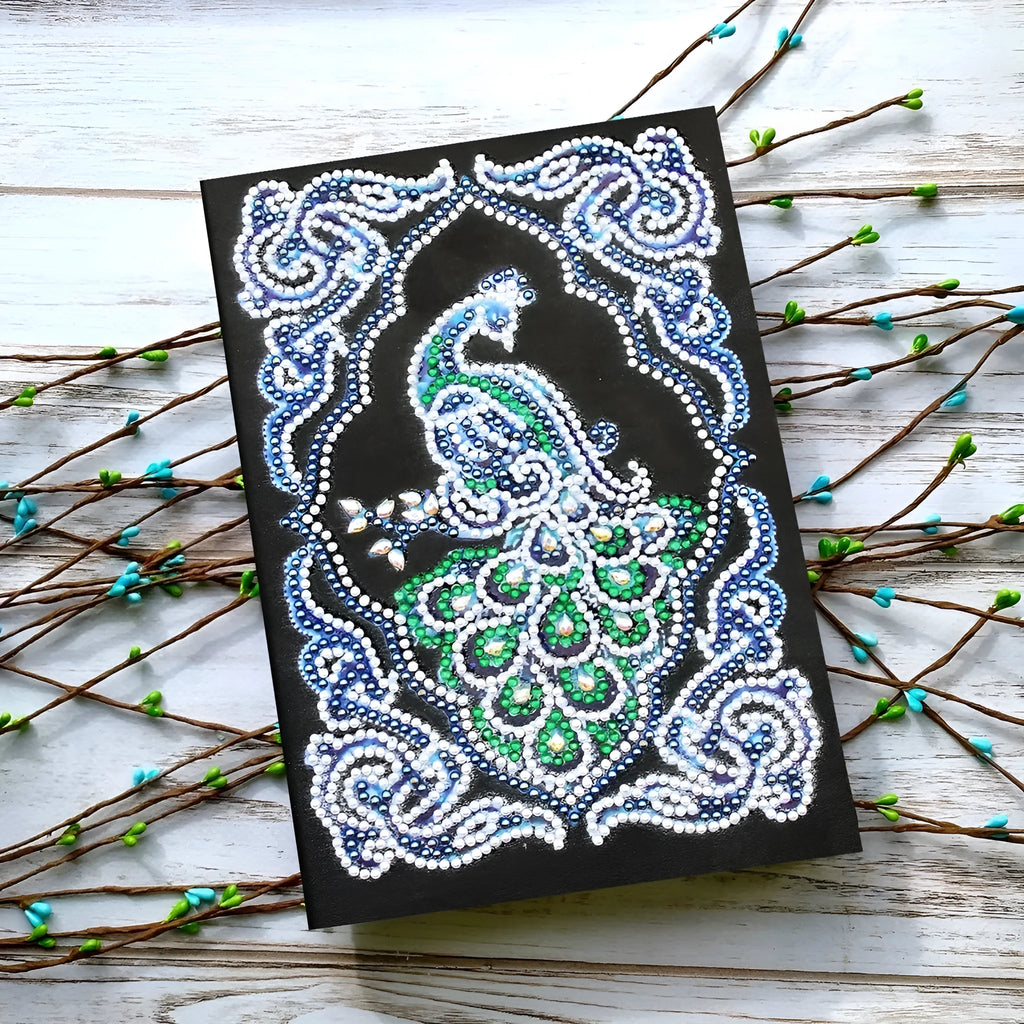 Black hardcover A5 diamond painting notebook with peacock beauty design, showing dimensions 142mm by 207mm.