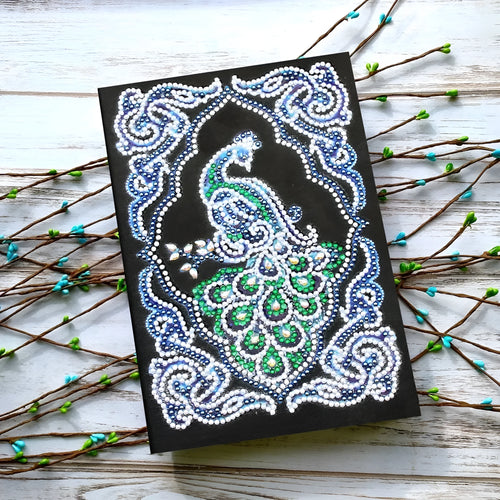 Black hardcover A5 diamond painting notebook with peacock beauty design, showing dimensions 142mm by 207mm.