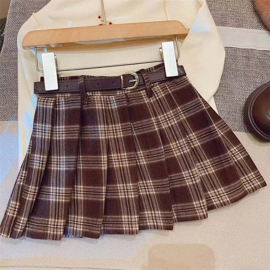 A girls' plaid pleated skirt in an A-line style, shown in a casual setting.