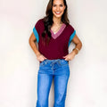 Burgundy women's loose sweater with contrast trim, V neck, and cuffed short sleeves.