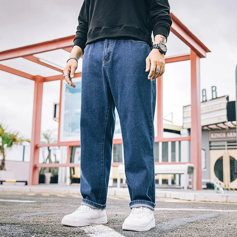 Man wearing loose straight-leg casual jeans in dark blue cotton fabric.
