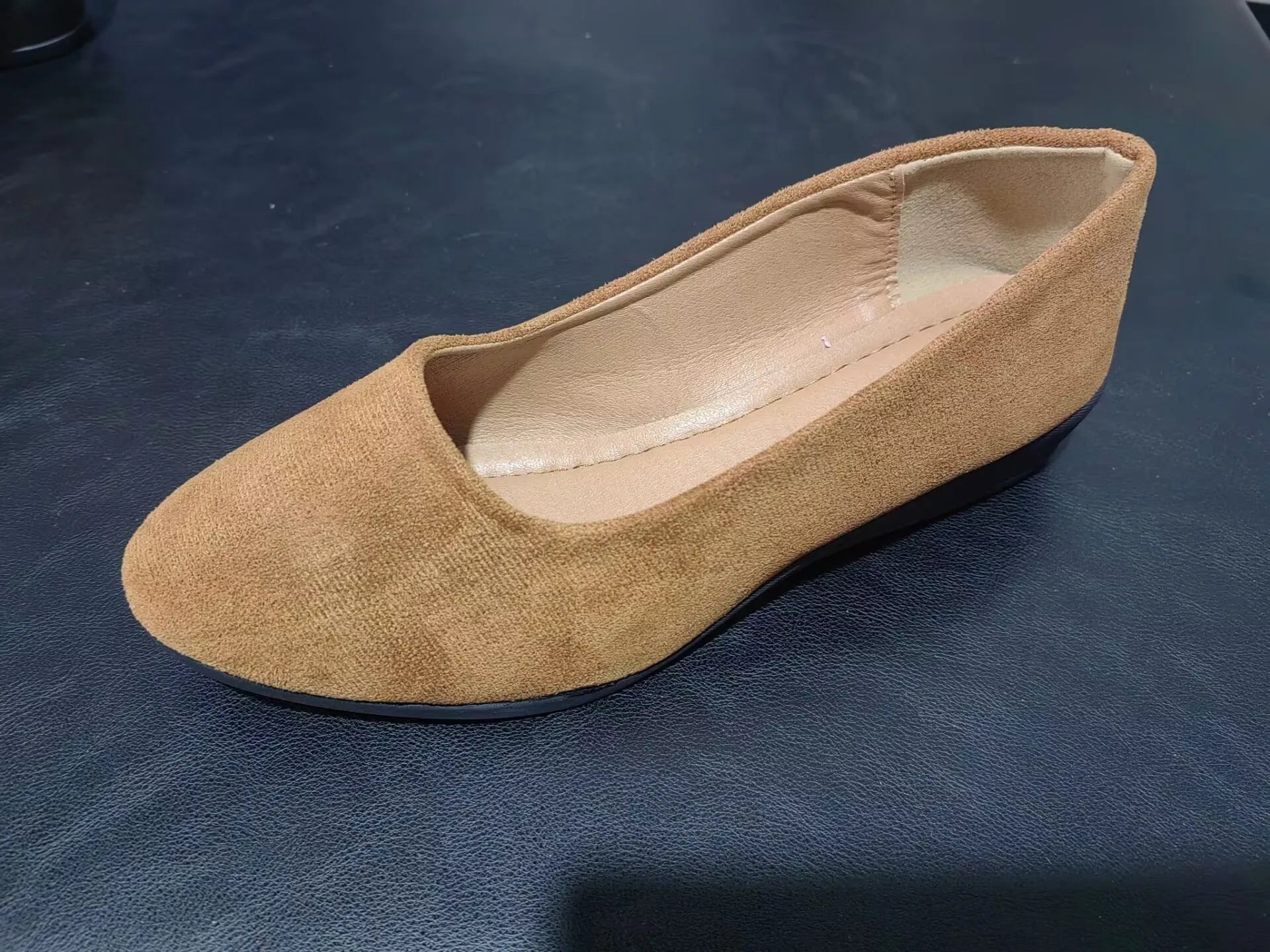 Women's suede wedge pump in light brown with a pointed toe and low rubber sole.