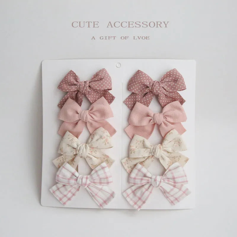Set of eight fabric hairclips with dovetail bows in a chosen colour like beige grid dots or pink.