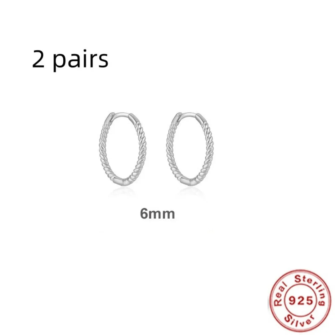A pair of twisted sterling silver round earrings in a geometric design on a white background.