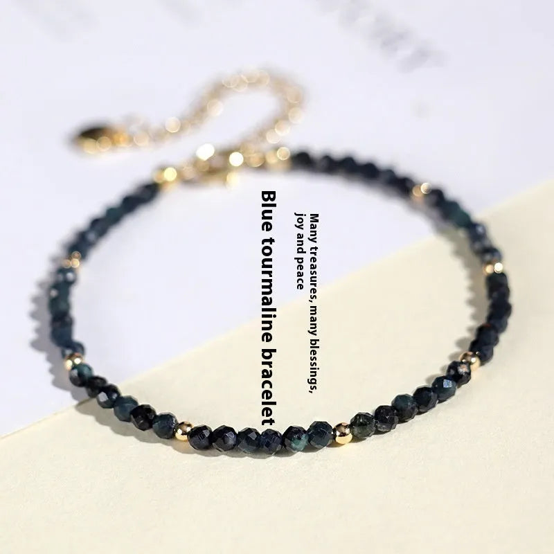 Close-up of a women's blue tourmaline bracelet with 3mm beads and gold spacer beads.
