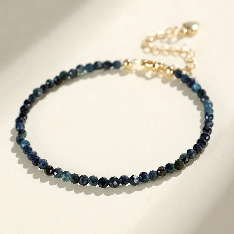 Close-up of a women's blue tourmaline bracelet with 3mm beads and gold spacer beads.