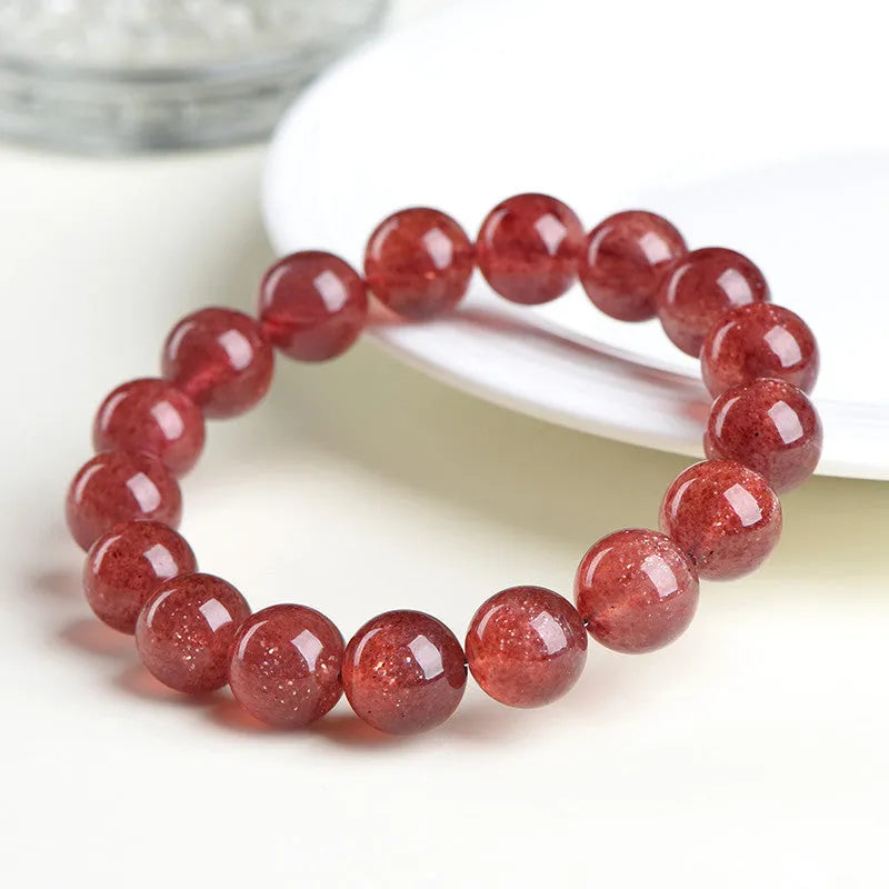Natural strawberry quartz bracelet with geometric red crystal beads on a white background