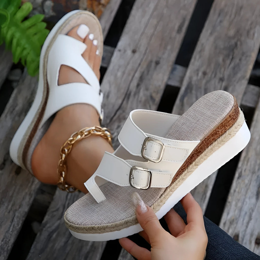 White patent leather women's wedge sandals with woven finger fit straps and a peep toe.