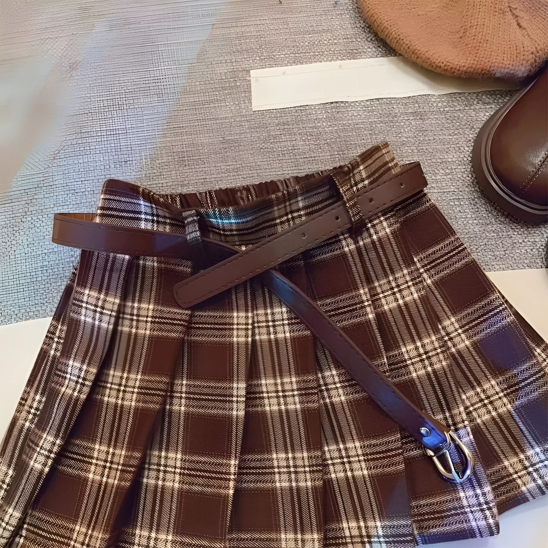 A girls' plaid pleated skirt in an A-line style, shown in a casual setting.