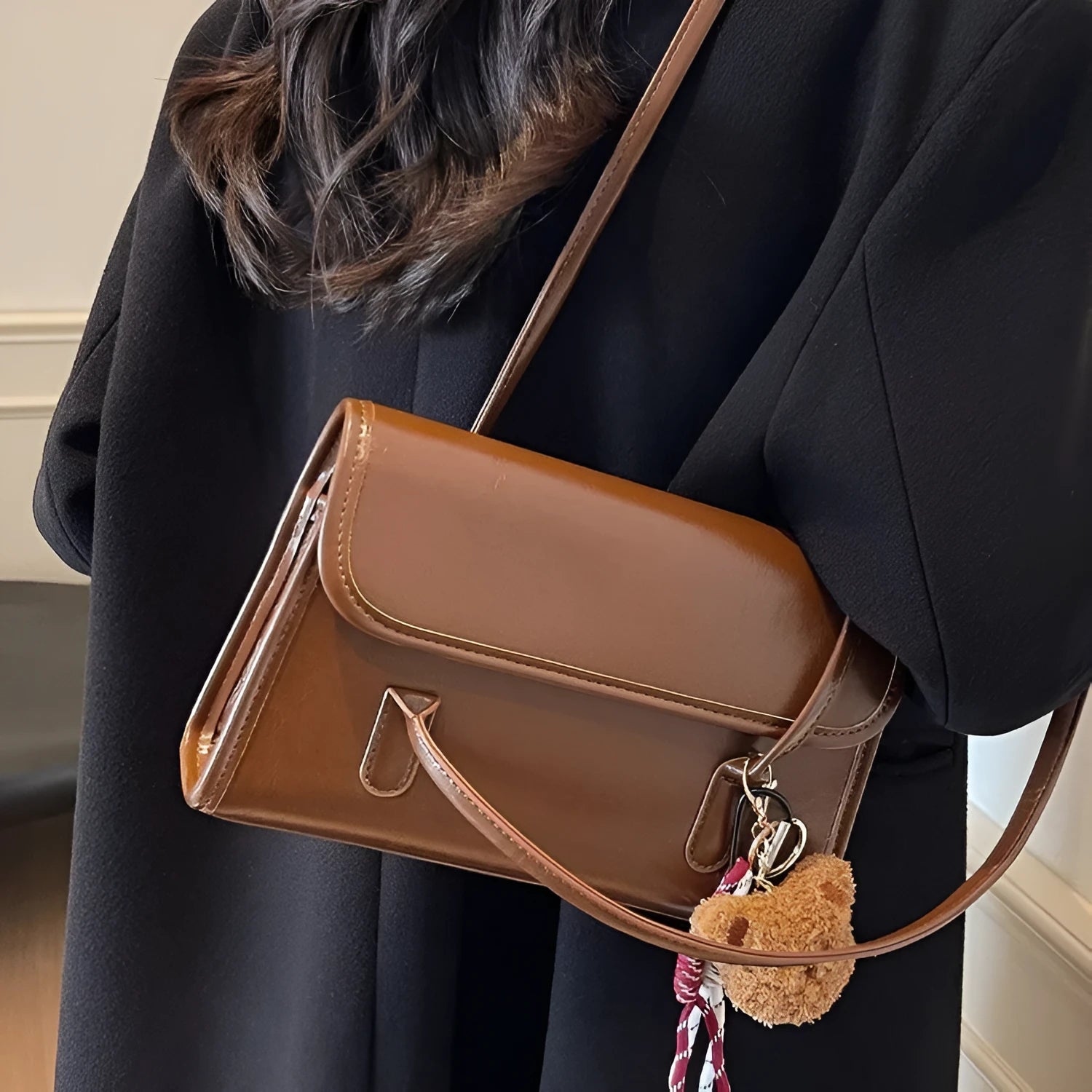 Brown women's square PU shoulder bag with a detachable pendant on a table