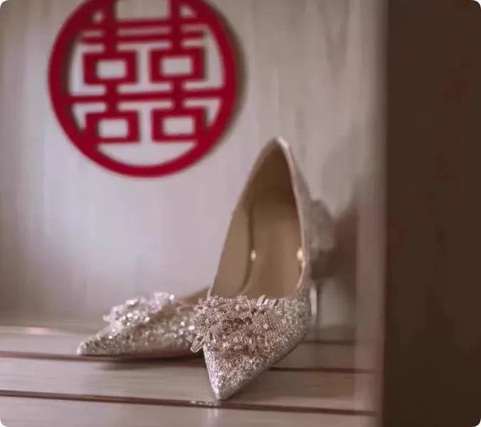 Champagne pointed-toe women's bridal shoes with floral rhinestone detail on a white background
