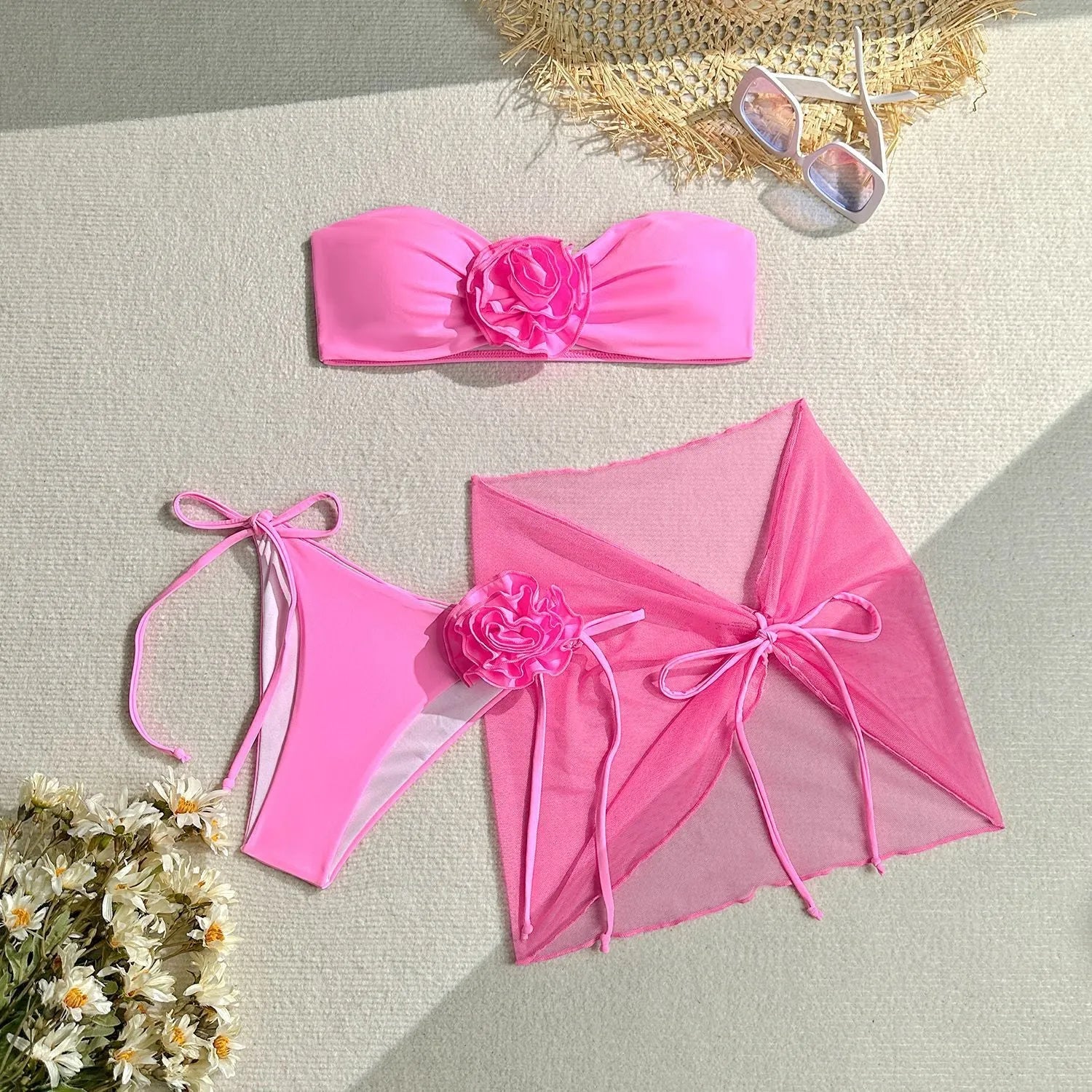 Women's pink tube top bikini with large 3D flower, matching bottoms, and skirt laid flat.