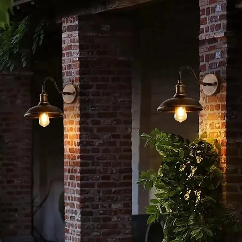 Retro style metal wall lamp in copper finish mounted on a stone wall.