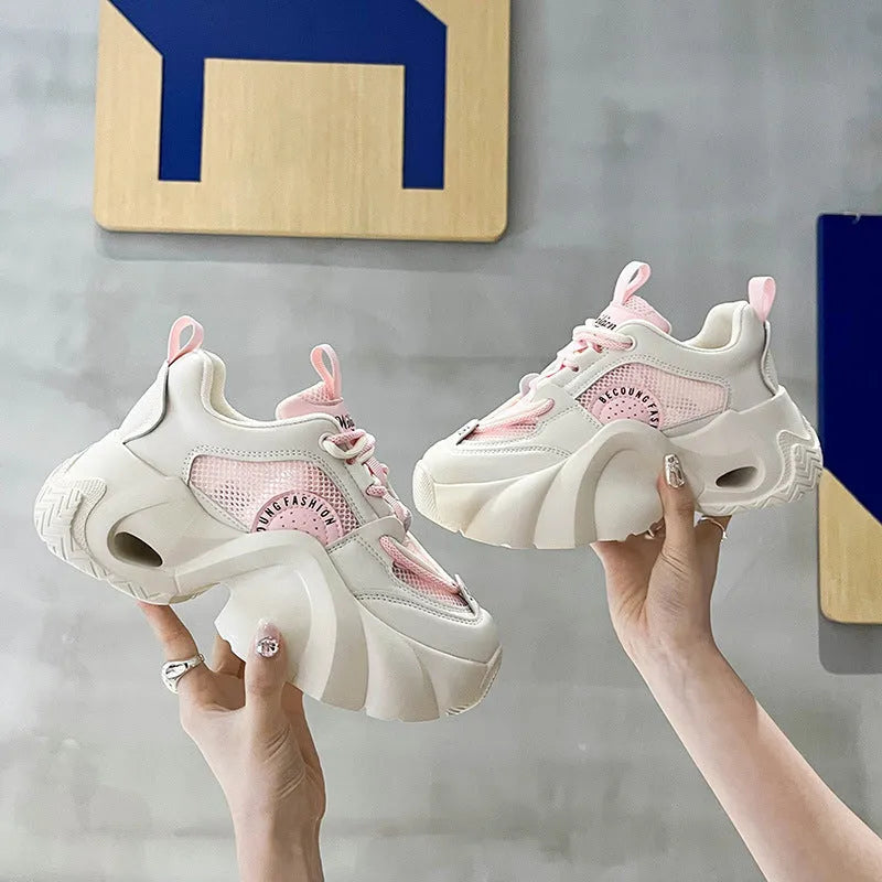 Women's pink sneakers with cross straps and a thick white platform sole.