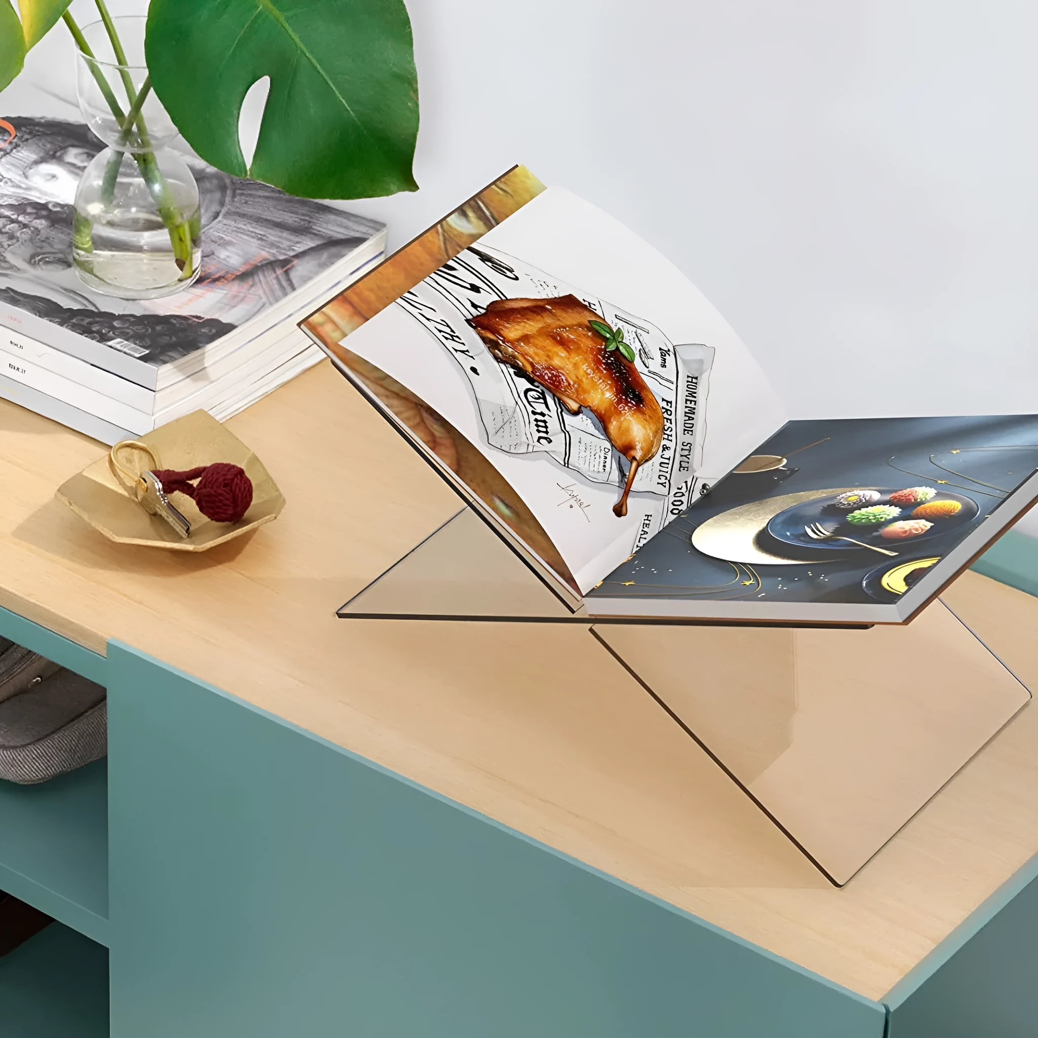 Clear acrylic X-shaped book reading rack holding books on a desk.