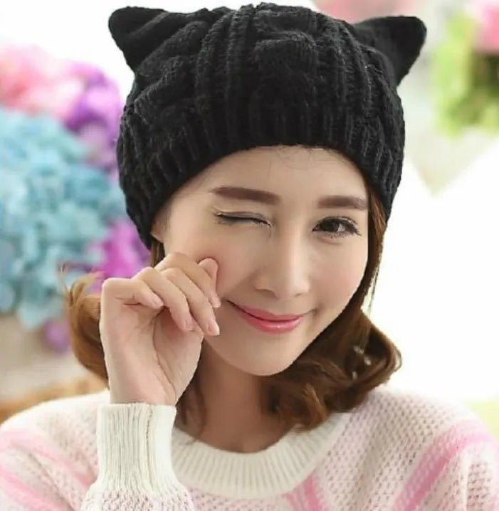 Handmade red knitted beanie with 3D cat ears on a white background.