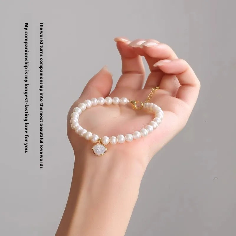 Freshwater pearl bracelet with fan-shaped shell setting and elastic string or extension chain fastening.