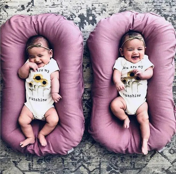 Beige portable cotton baby nest crib for newborns measuring 75cm by 45cm on a neutral background