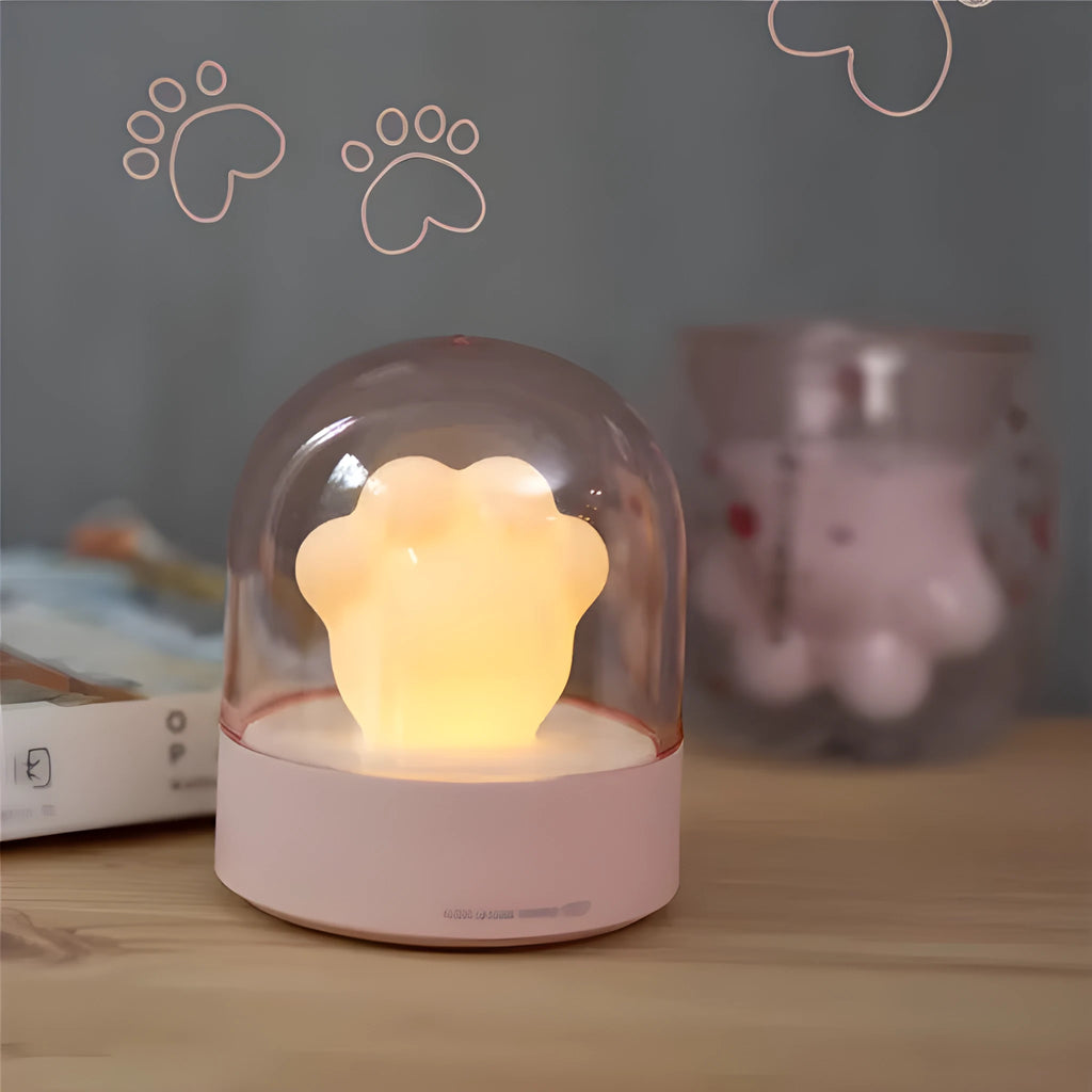 Pink and grey cat paw shaped USB night light with a music box feature on a desktop.