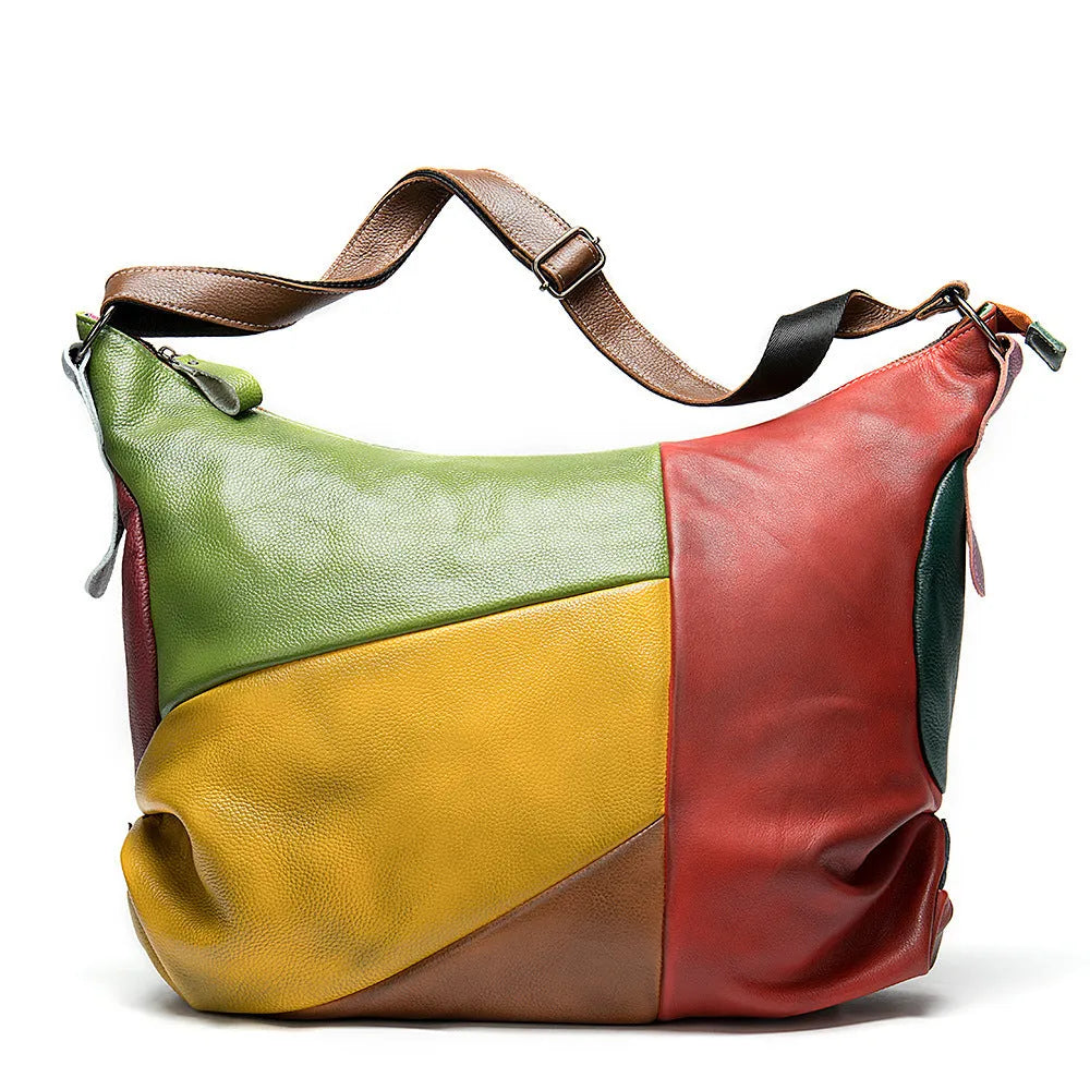 Brown cowhide leather travel bag with crossbody strap, shown next to a laptop and tablet.
