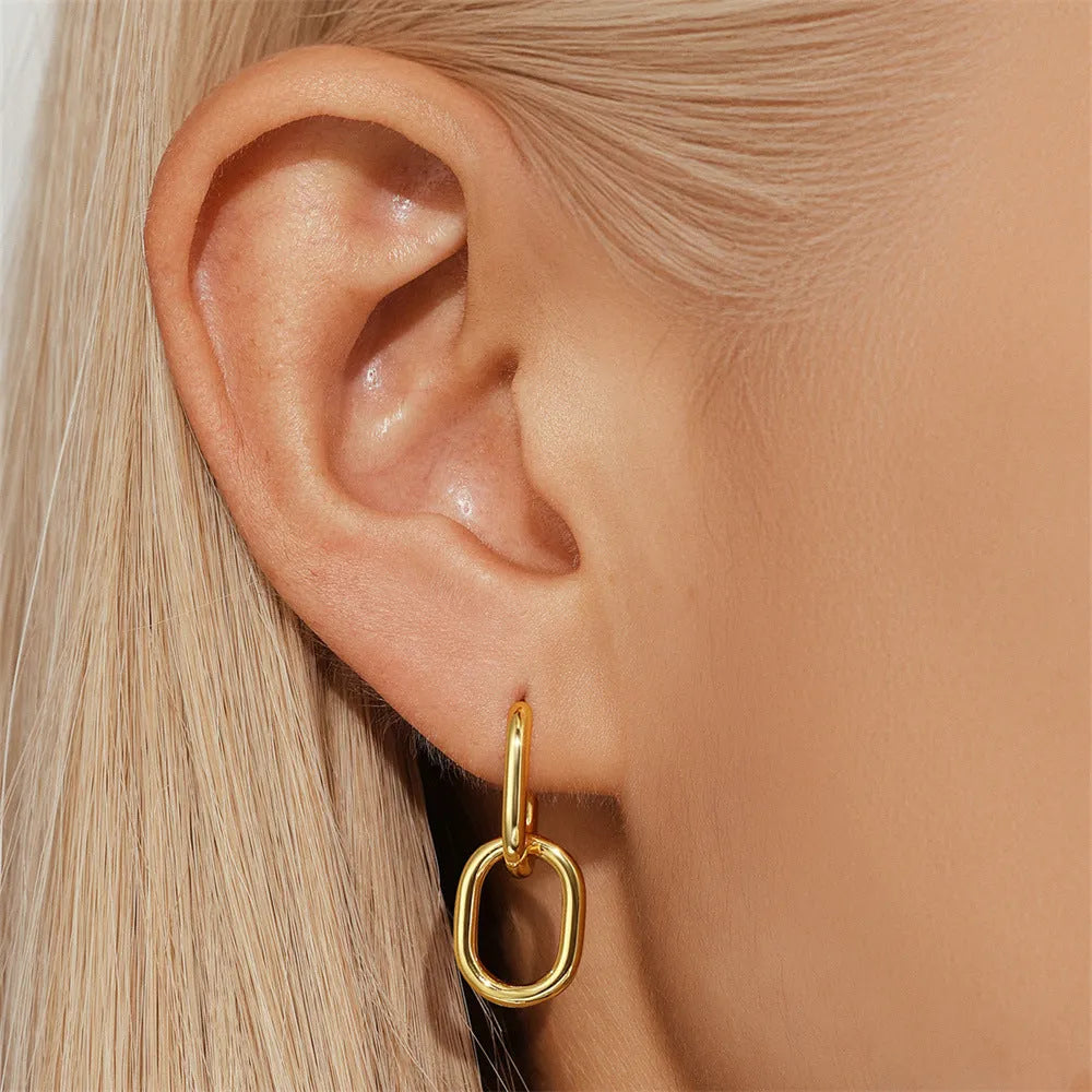 Golden brass earclip earrings with geometric round drop design on white background