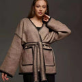 Lace-up front knitted cardigan sweater coat in camel colour, showing loose fit and long sleeves.