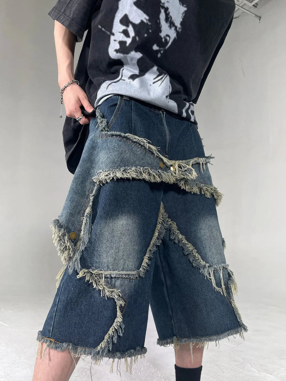 Blue men's denim shorts with a frayed hem and a large five-pointed star design on the leg.