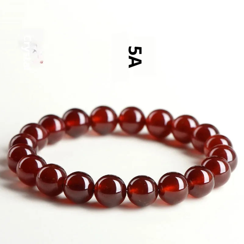 Natural orange red garnet crystal bead bracelet with a ruyi charm on a wrist.