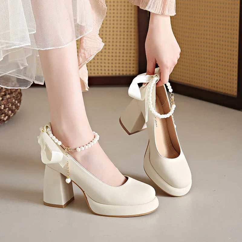 Women's beige Mary Jane shoes with a chunky heel and an ankle-strap buckle on a round toe.