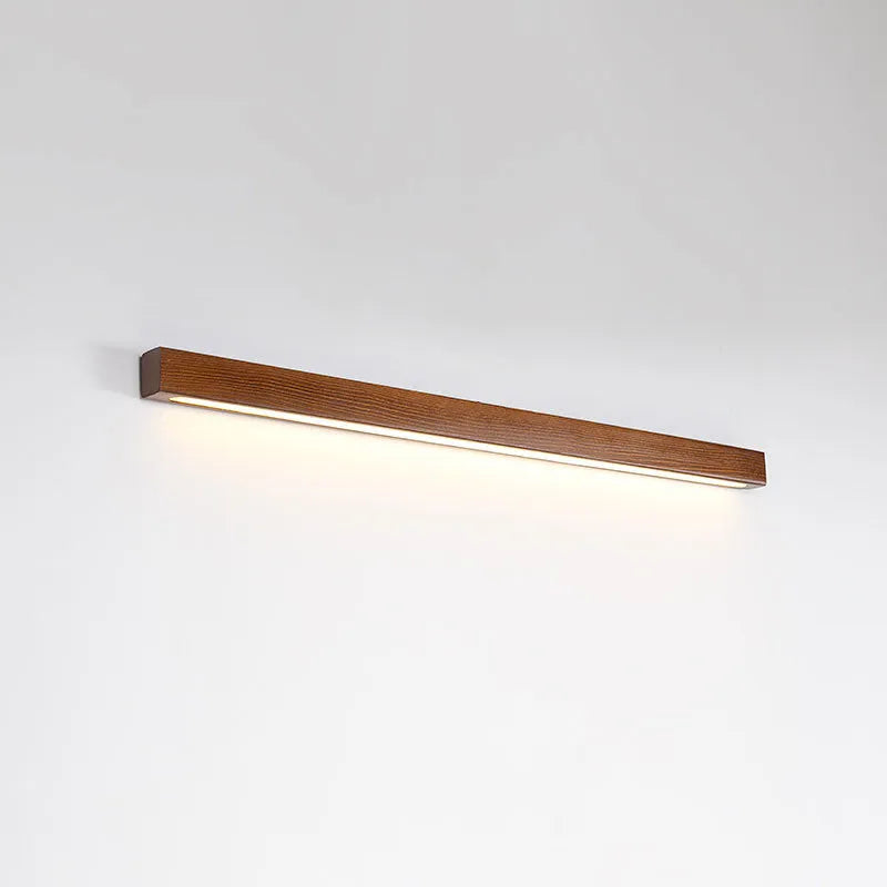 Walnut colour minimalist wooden and acrylic strip wall lamp in three length options on a white wall.
