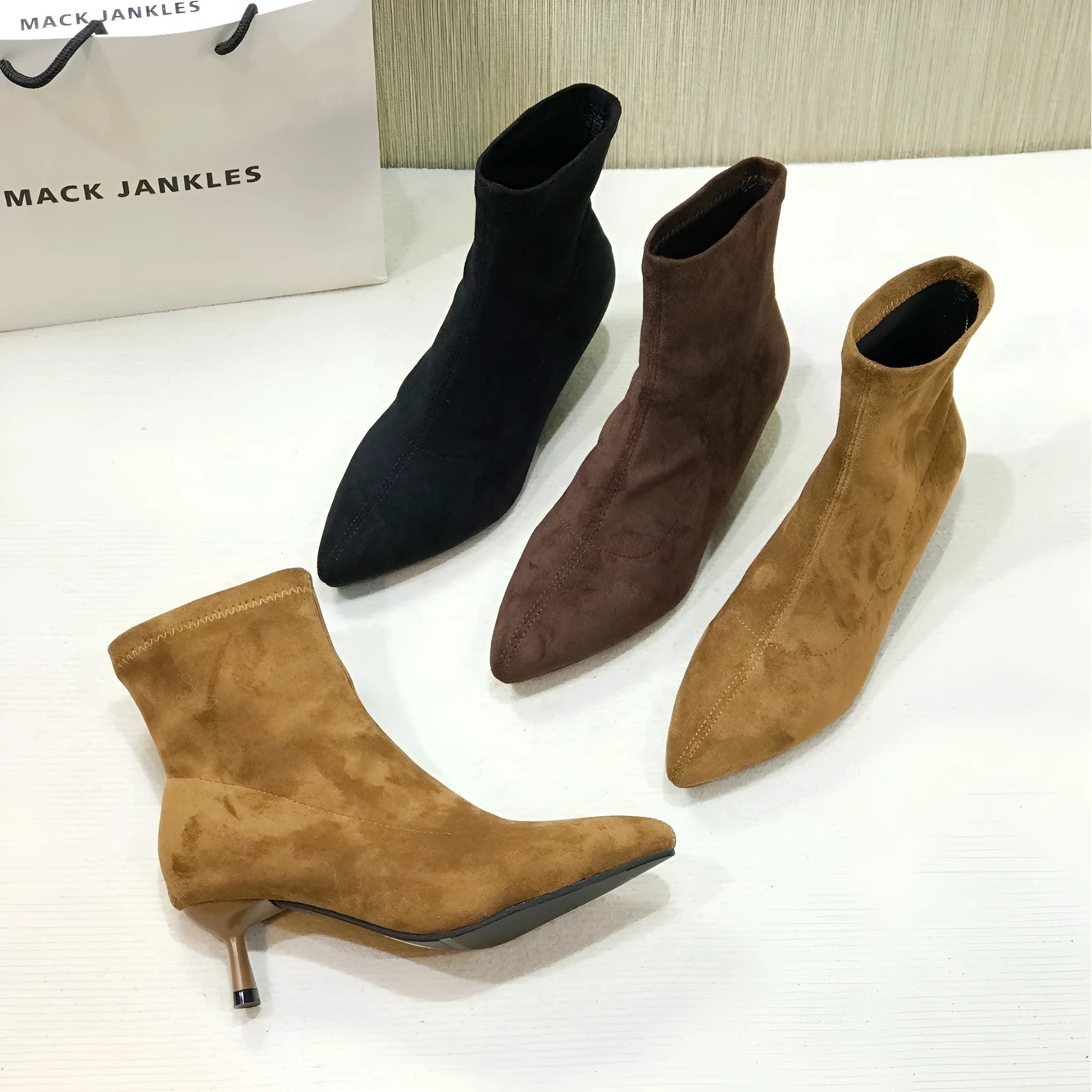 Black pointed toe stiletto ankle boots with a mid-calf sock length on a model.