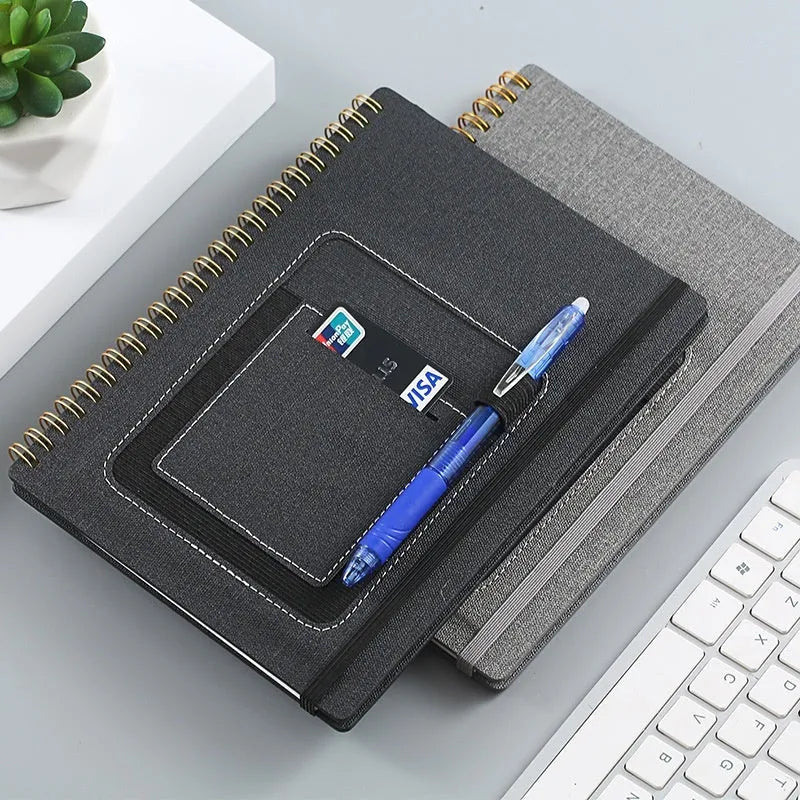 Erasable coil-bound notebook with customisable coloured cover on thick, reusable rock paper, shown with a pen.