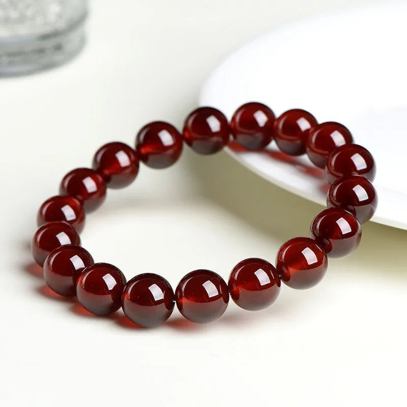Natural orange red garnet crystal bead bracelet with a ruyi charm on a wrist.