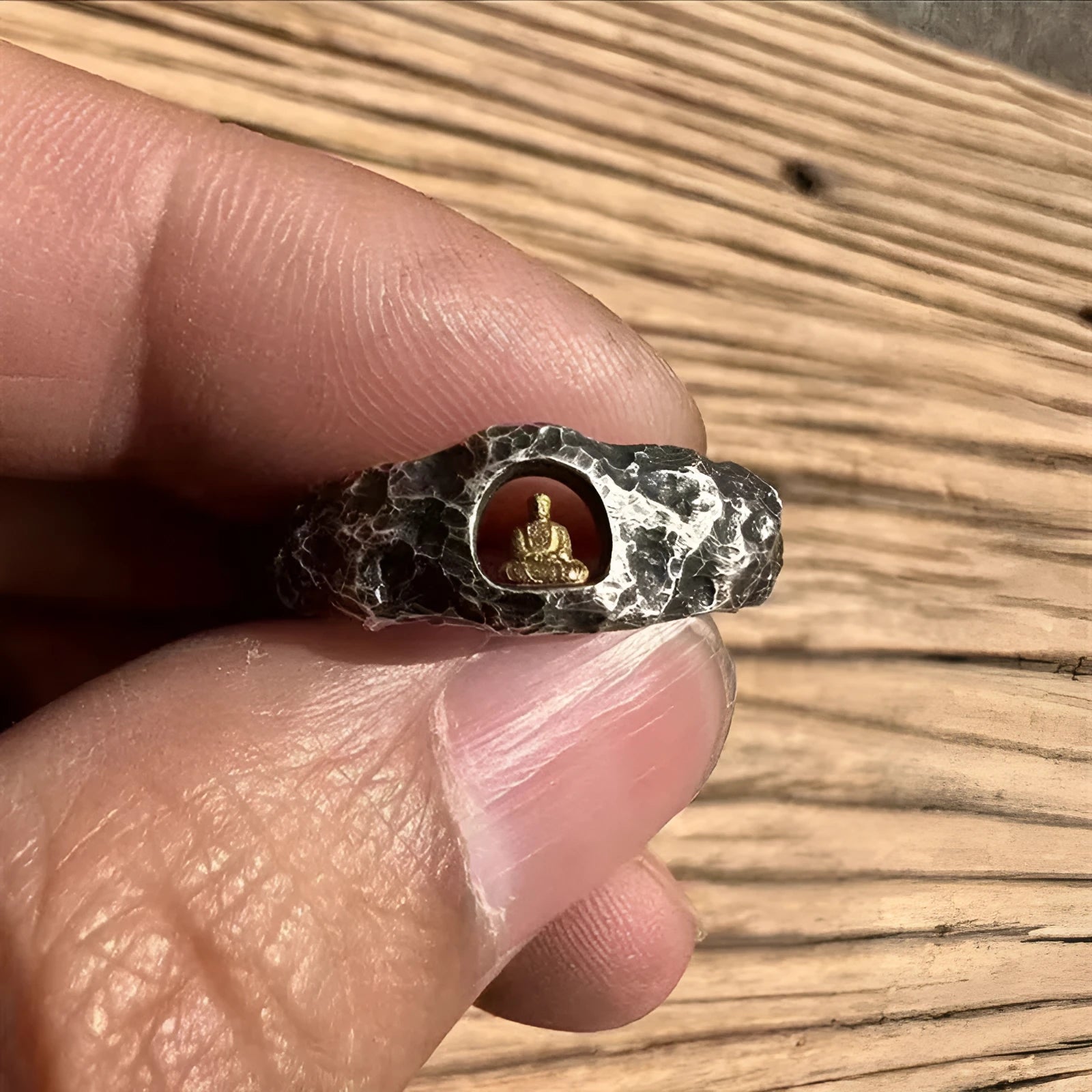 Hand-forged copper Grotto Buddha ring with a rock-textured surface, shown on a size 8 finger.