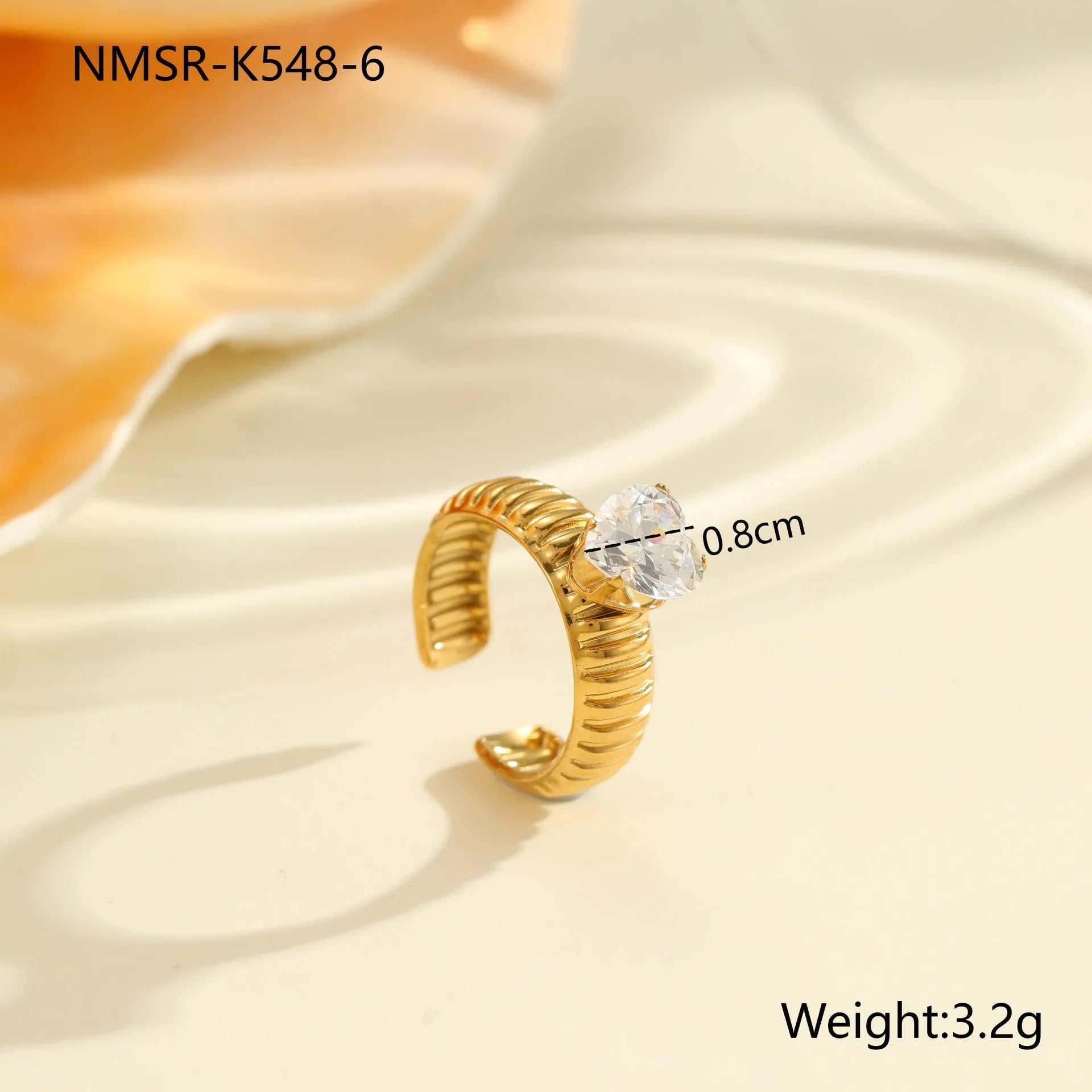 Gold inlaid zircon geometric heart and drop shape stainless steel ring on white background.