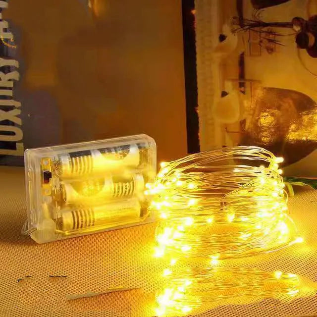Copper wire LED string lights shaped around a bottle, showing multiple small coloured bulbs.
