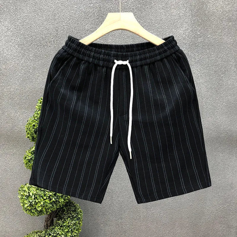 Man's black and white striped casual shorts with elastic waistband on a plain background.