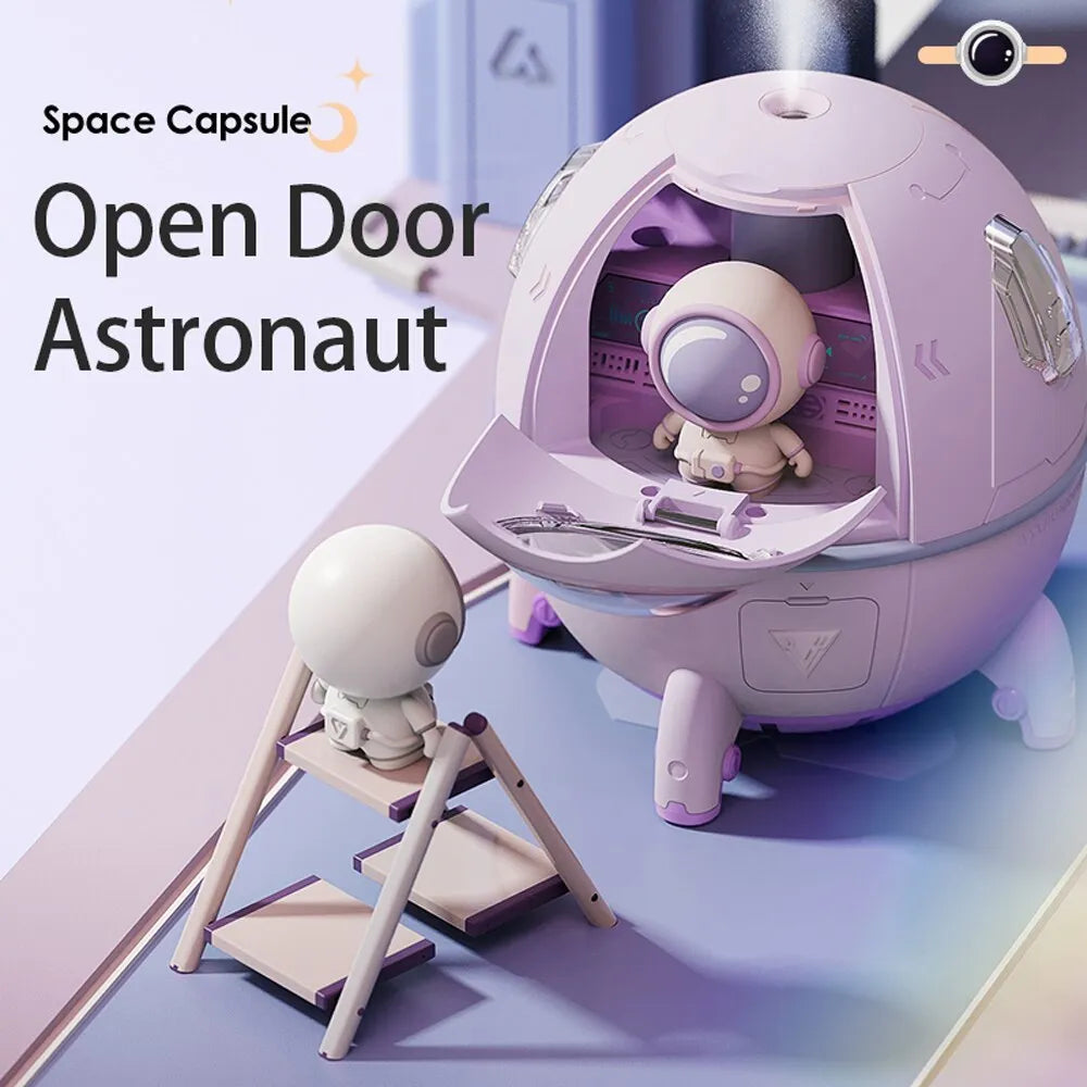 Purple astronaut-shaped USB desktop humidifier with LED light on a desk next to a laptop.