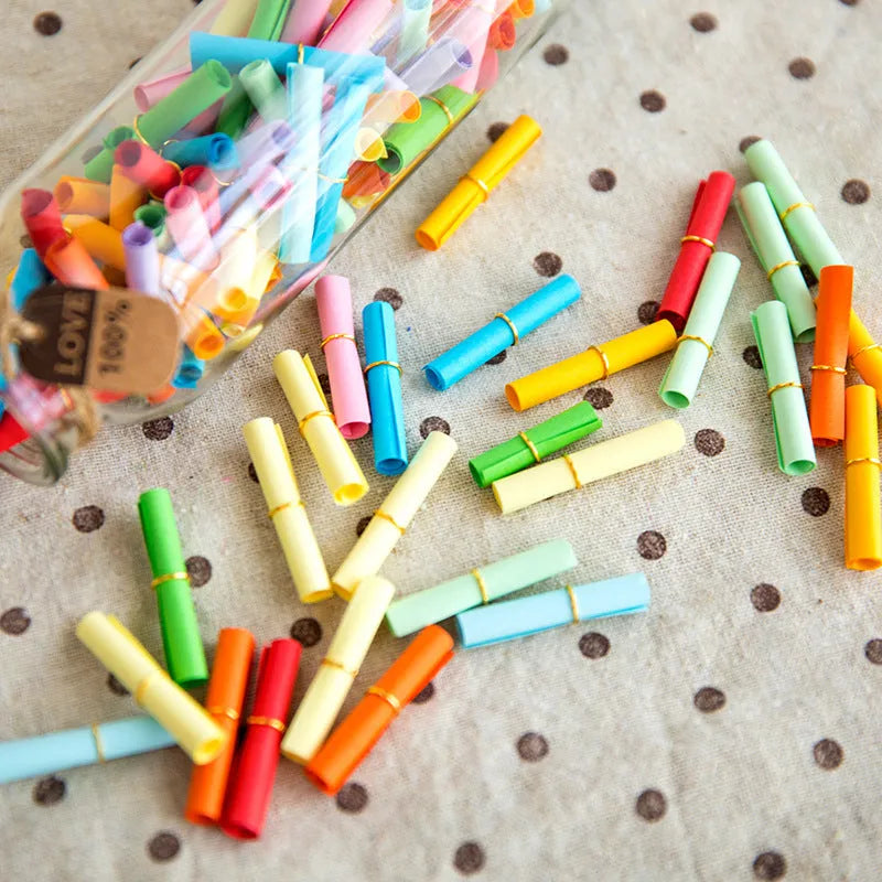 Assorted colourful paper scrolls with metal eyelets for messages and craft projects.