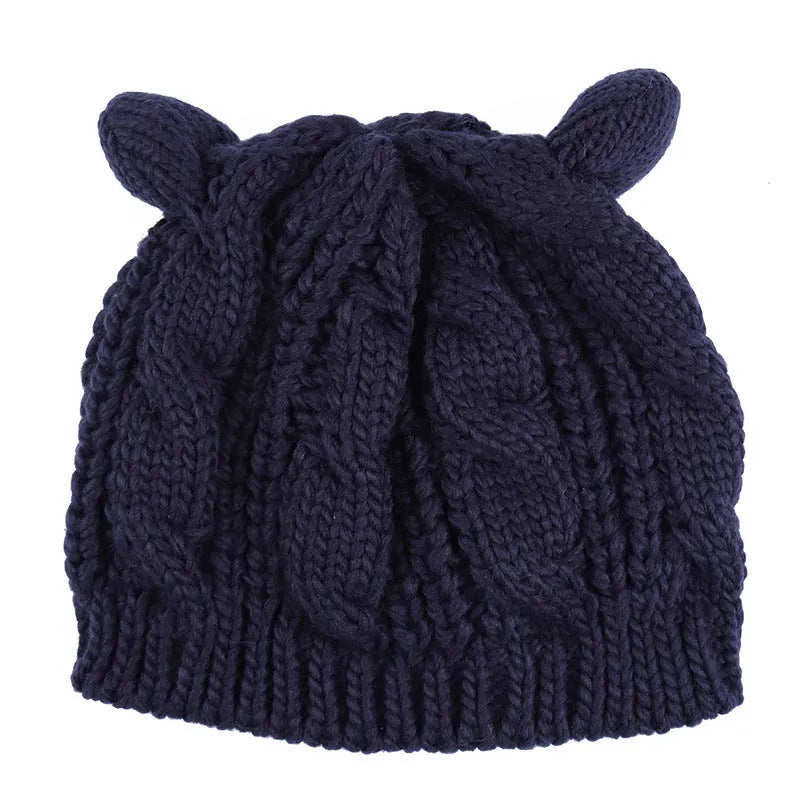 Handmade red knitted beanie with 3D cat ears on a white background.