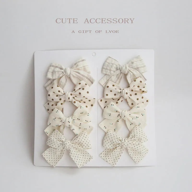 Set of eight fabric hairclips with dovetail bows in a chosen colour like beige grid dots or pink.