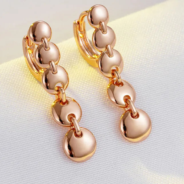 A pair of long gold-colour retro earrings with a woven round circle design made from copper.