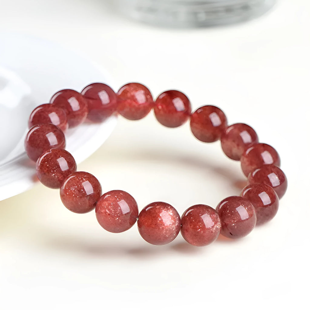 Natural strawberry quartz bracelet with geometric red crystal beads on a white background
