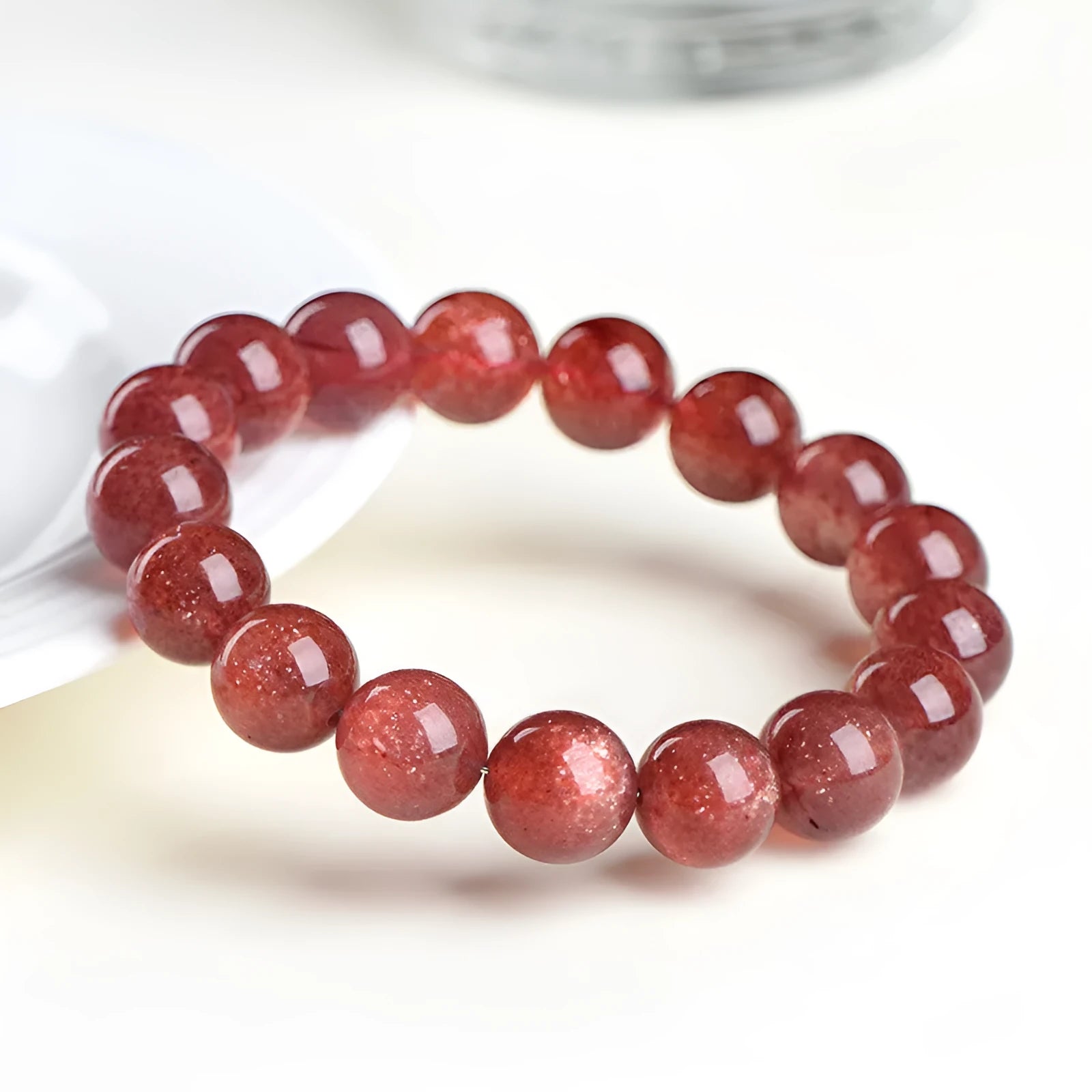 Natural strawberry quartz bracelet with geometric red crystal beads on a white background