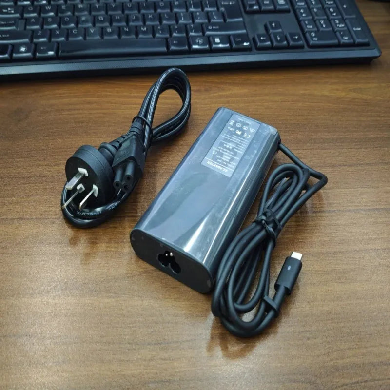 Black oval 65W USB-C laptop power adapter with Type-C port and multiple international power cords