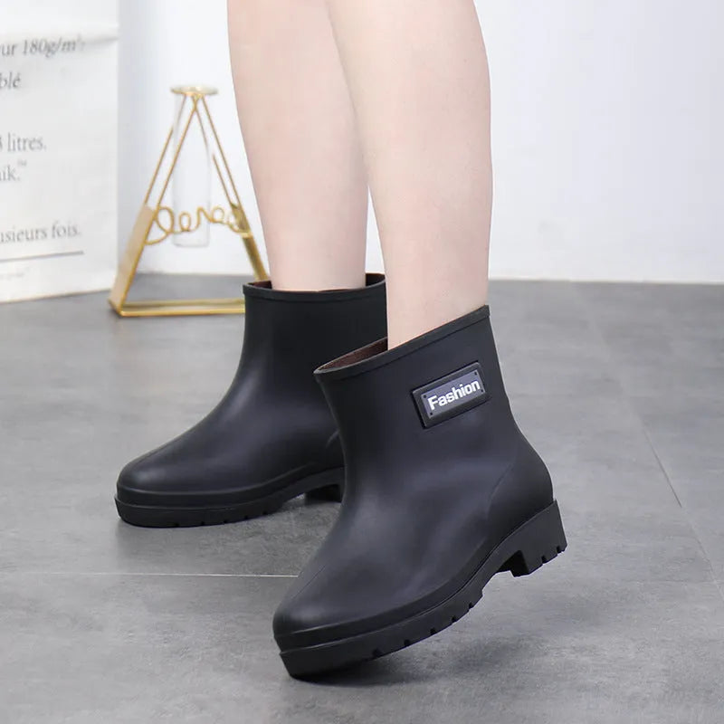Women's mid-calf PVC rain boot in black with a low heel on a white background.